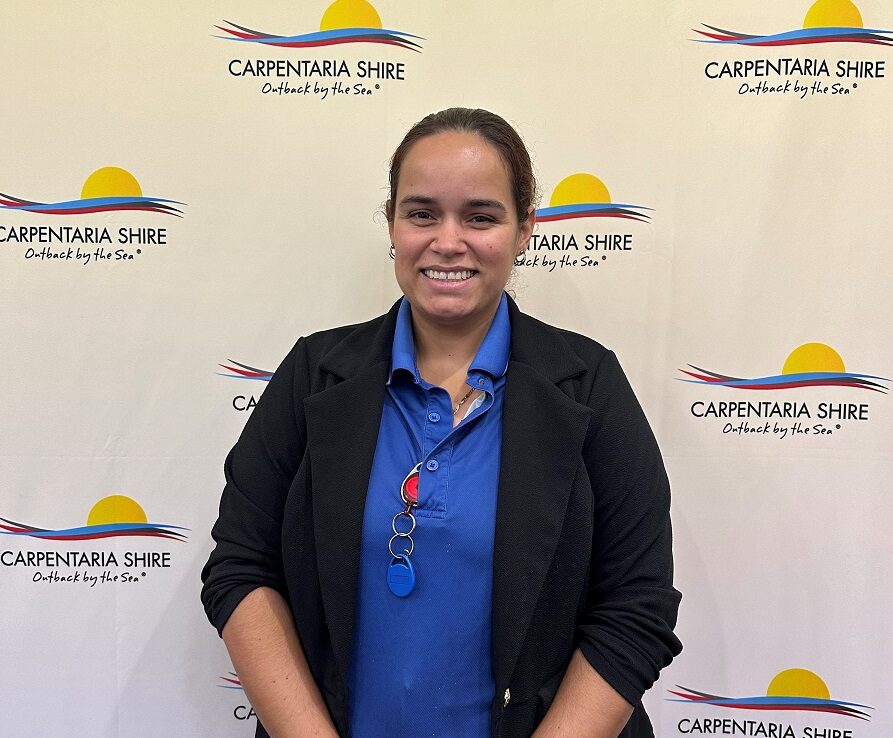 Young, First Nation's female stands in front of Carpentaria shire council media wall.